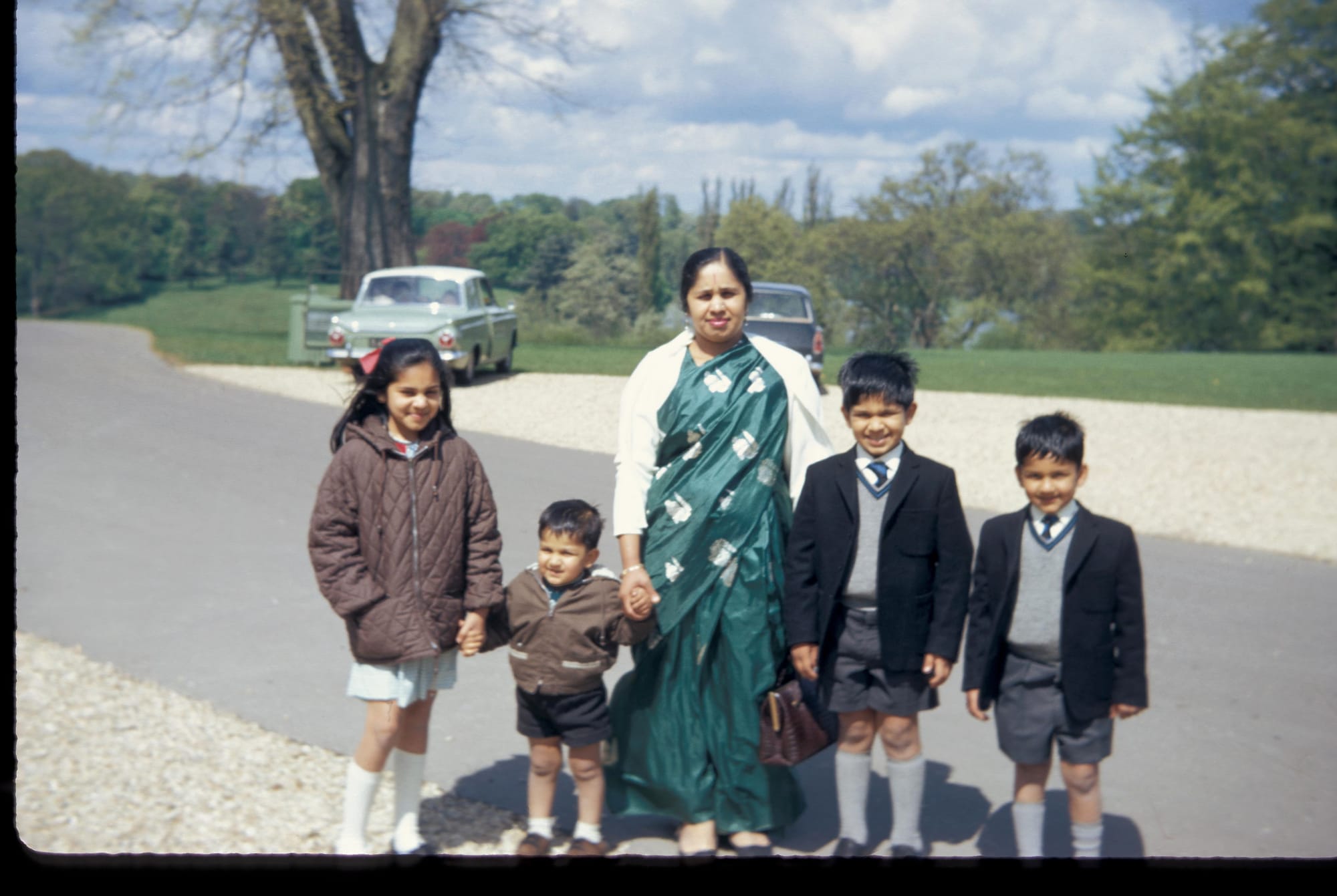 Mataji and all four children: Veena (eldest, anorak), Anil and Sunil (blazers), Ravi (toddler). Sunil is far right. An English park